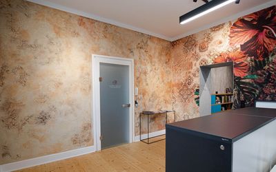 Empfangsbereich mit gemusterter Wand und dunkler Theke