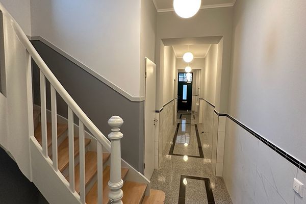Renovierter Hausflur in Aachen mit grauem Wandsockel und weißem Treppengeländer