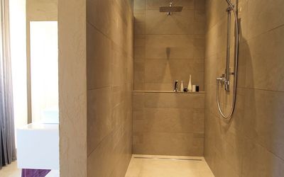 Dusche mit durchgehend gestalteten beigefarbenen Wandflächen