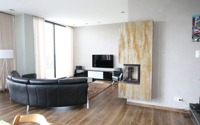 Wohnzimmer mit Kamin, dunklem Sofa und Holzfußboden
