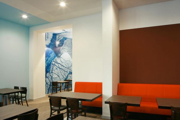 Sitzbereich mit orangefarbenen Polstern und blauem Wandmotiv im Alexianer Krankenhaus