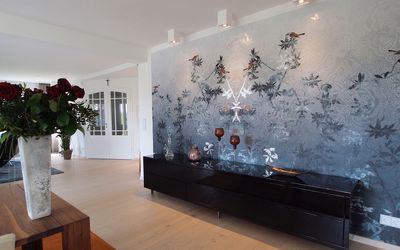 Wohnbereich mit floraler Wandgestaltung und dunklem Sideboard