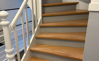 Holztreppe mit grauen Setzstufen und weißem Geländer