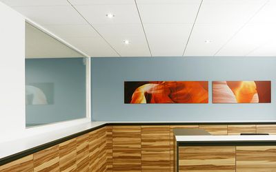 Praxisempfang mit Holzfront, grauer Wand und Bildreihe