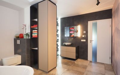 Badezimmer mit freistehender Wanne und dunklen Wandflächen
