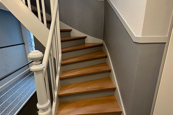 Renovierter Treppenaufgang mit grauem Wandsockel und weißen Zierleisten