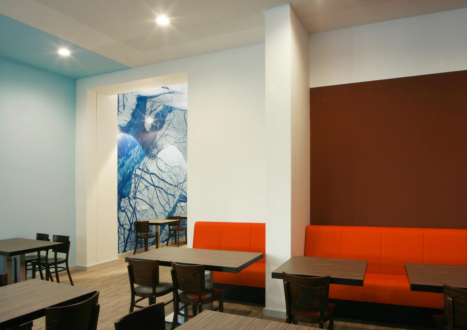 Sitzbereich mit orangefarbenen Polstern und blauem Wandmotiv im Alexianer Krankenhaus