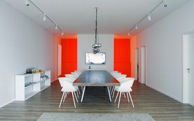 Besprechungsraum mit orangefarbenen Wandflächen und langem Tisch